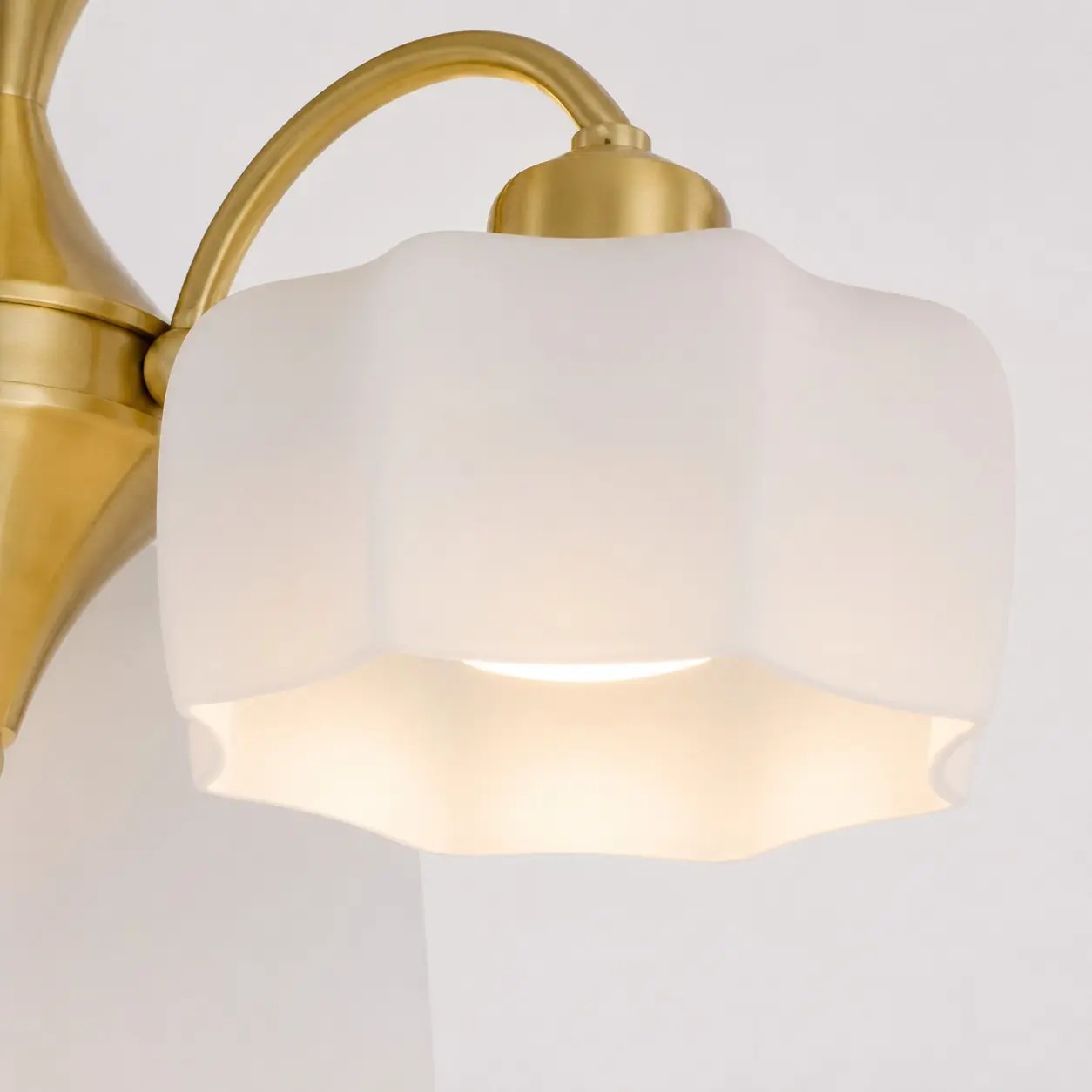 White glass flower-shaped shade and gold lamp holder detail