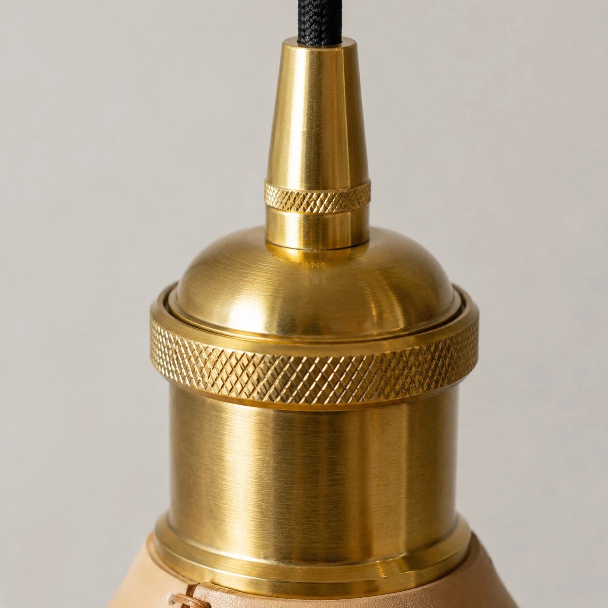 Brass tone cap and cord detail on cone pendant