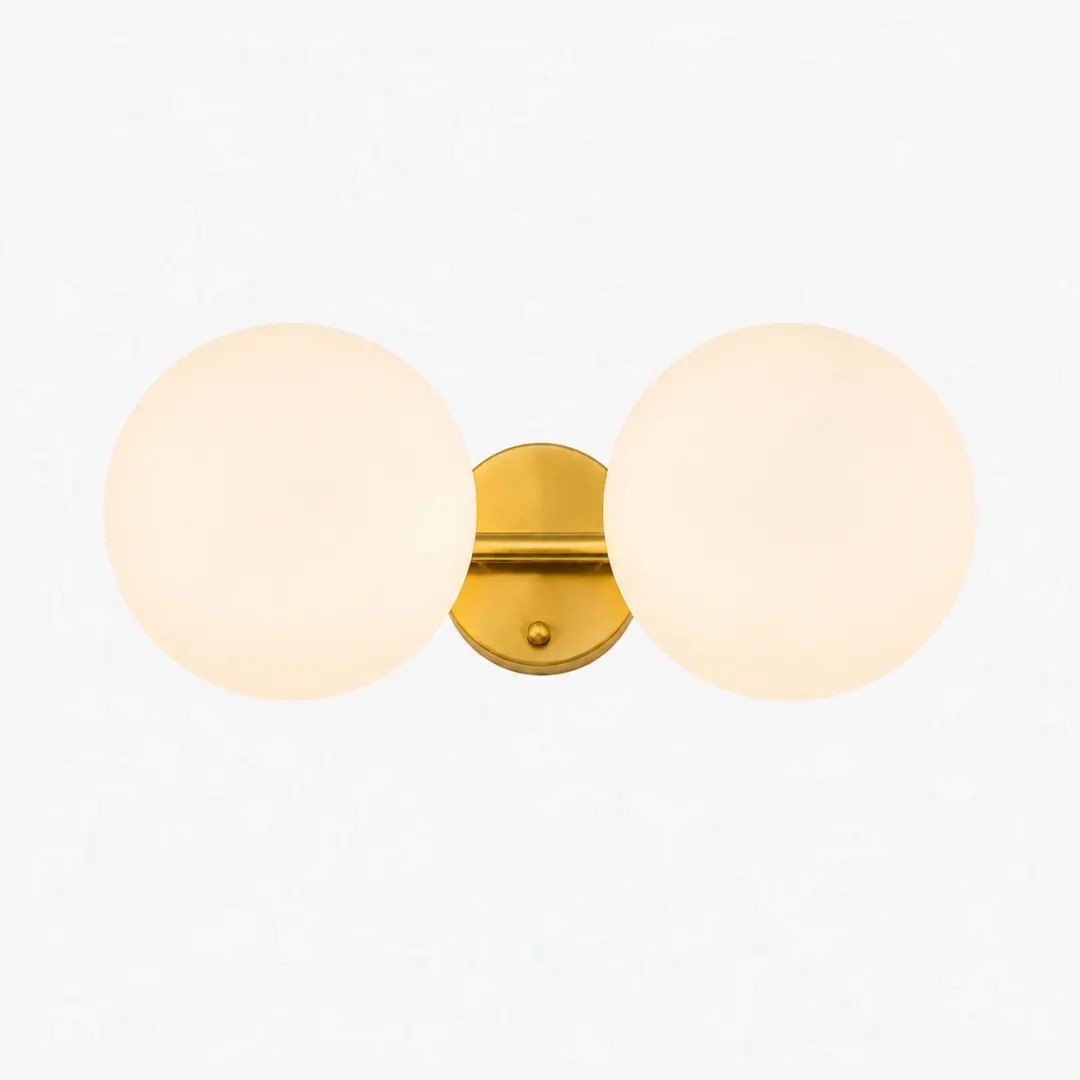 Lámpara de tocador dorada de dos luces con globos de cristal opalino.