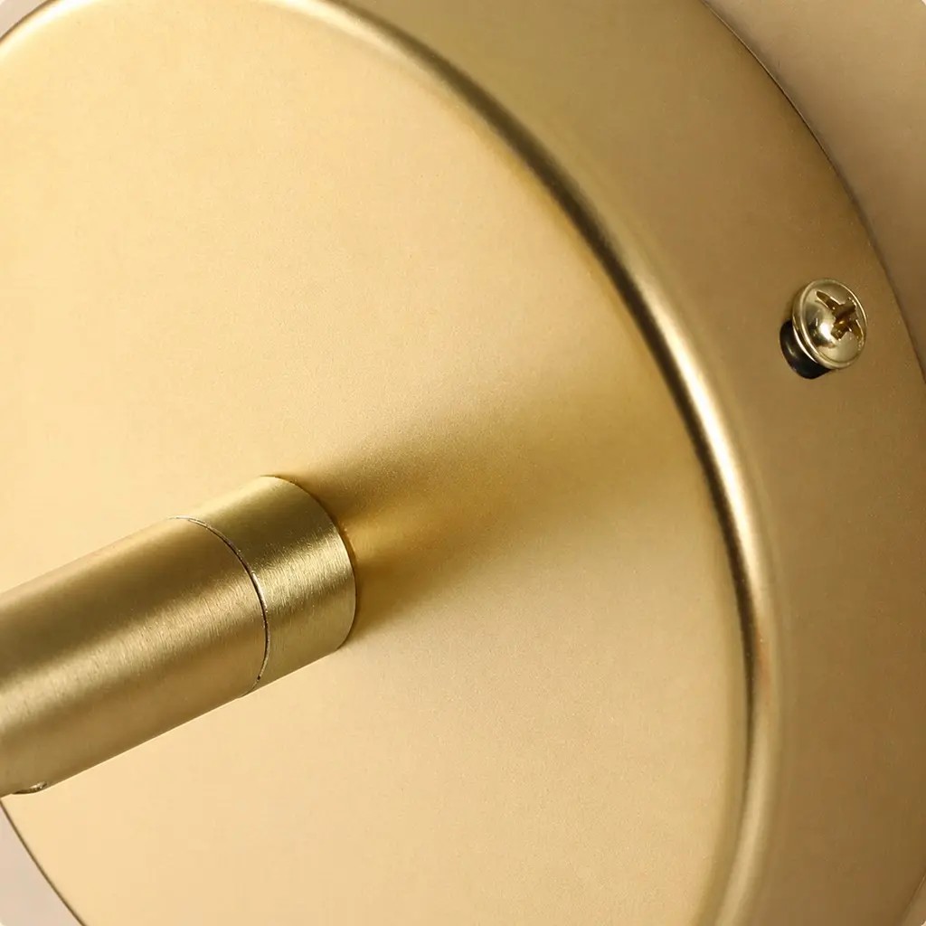 Primer plano de la placa redonda dorada para pared y los tornillos de fijación.