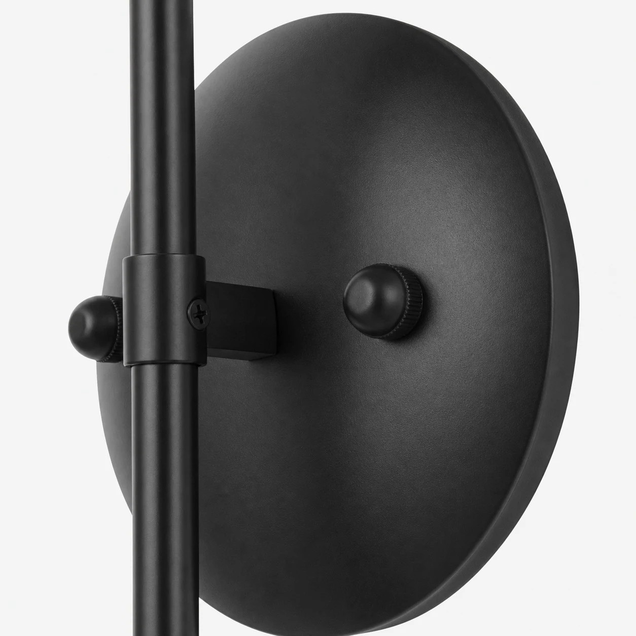 Detail van de zwarte metalen wandplaat en armaansluiting