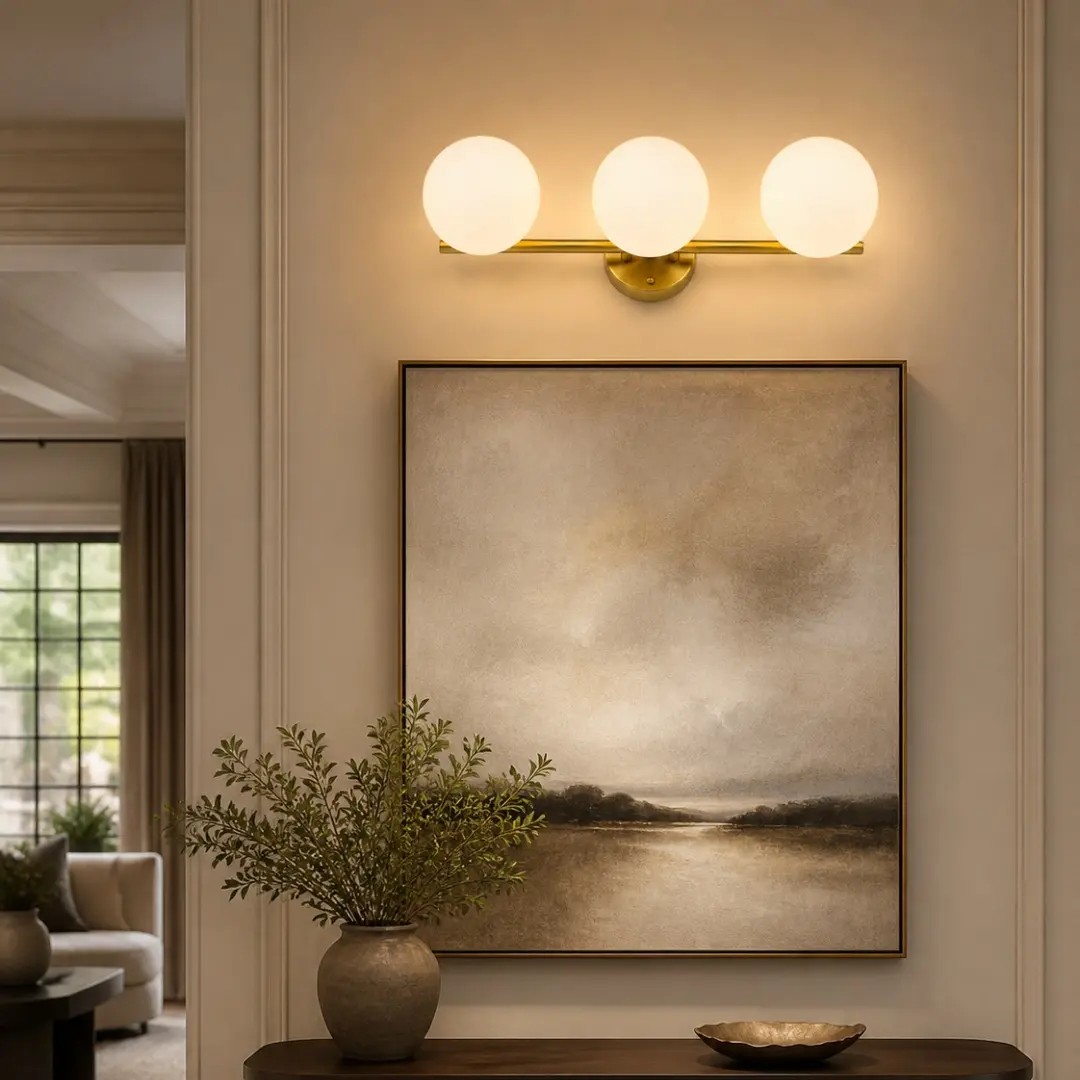 Three-light gold milk glass wall light above a console