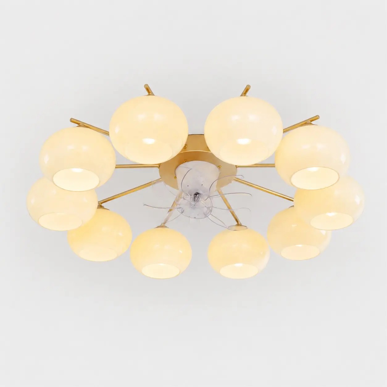 Moderne plafondventilator met 10 lampen in goudkleur en witte glazen kappen.