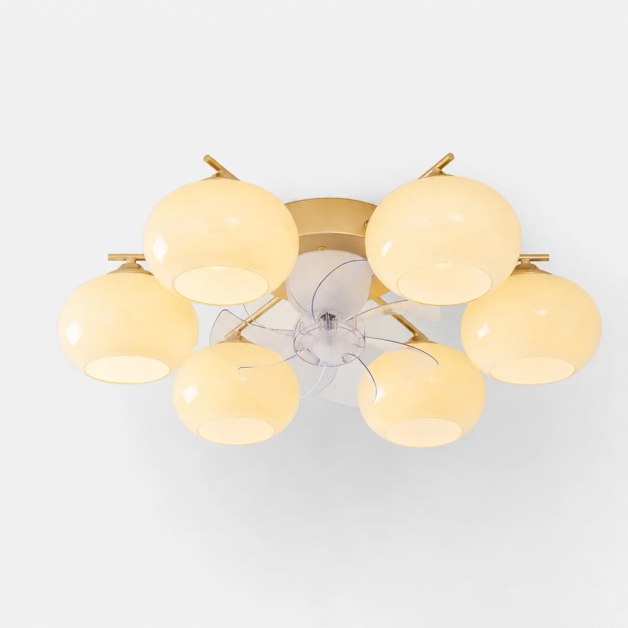 Moderne plafondventilatorlamp met 6 lampen in goudkleur en witte glazen kappen.