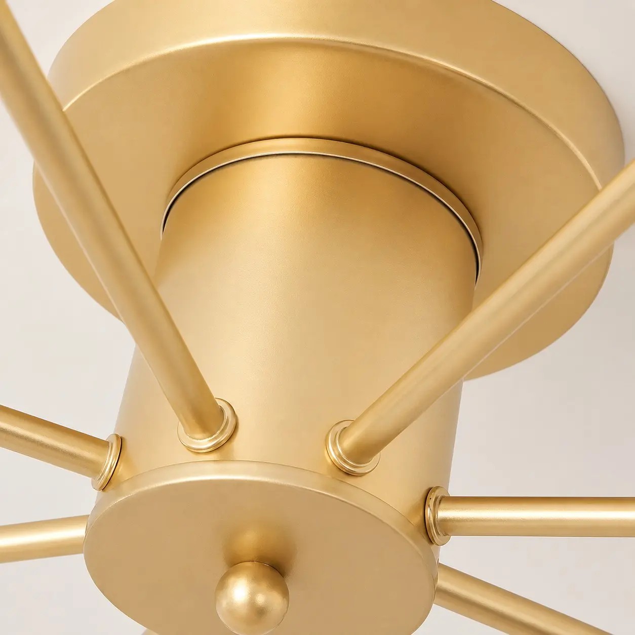 Detailopname van de gouden plafondkap en armverbindingen.